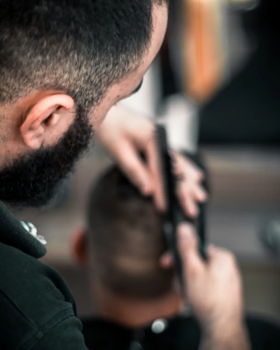 Barbero aplicando un fade de precisión con máquina y peine