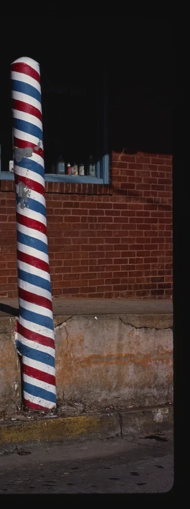 Poste de barbería en penumbra junto a un muro de ladrillo